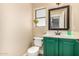 Charming powder room featuring a green vanity, a sleek mirror, and a bright window at 18563 W Fairway Dr, Surprise, AZ 85374