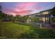 Exterior shot of backyard with green lawn, trees, and patio area at dusk at 1890 E Sagittarius Pl, Chandler, AZ 85249