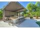 Modern outdoor kitchen with an extended bar, built-in grill, and ample seating under a shaded pergola at 1890 E Sagittarius Pl, Chandler, AZ 85249
