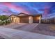 Attractive desert home with a 3-car garage, paver driveway, and well-manicured landscaping at sunset at 19873 W San Juan Ave, Litchfield Park, AZ 85340