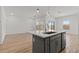Kitchen island with pendant lights, wood floors, stainless steel dishwasher, and an open-concept layout at 23443 W Albeniz Pl, Buckeye, AZ 85326