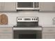 Close up of a modern electric range, gray cabinets and subway tile backsplash at 23443 W Albeniz Pl, Buckeye, AZ 85326