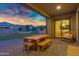 A covered patio with an outdoor dining set, rocking chair, and serene view of the backyard and beautiful sky at 3929 E Bloomfield Pkwy, Gilbert, AZ 85296