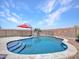 A backyard pool features stone coping, tiled steps, and a safety fence with a colorful patio umbrella at 4132 W Tunnel Mine Rd, New River, AZ 85087