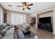 Spacious living room with tile floors, plantation shutters, neutral paint, a ceiling fan, and an open view to the kitchen at 4366 E Lexington Ave, Gilbert, AZ 85234