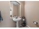 Cozy powder room featuring a pedestal sink, arched mirror, and neutral color palette at 4366 E Lexington Ave, Gilbert, AZ 85234