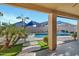 A beautiful backyard with a pool viewed from a covered patio area with neutral tones and green outdoor space at 4493 E Desert Sands Dr, Chandler, AZ 85249