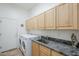 Functional laundry room with sink, granite counters, ample storage, and modern appliances at 7486 E Bajada Rd, Scottsdale, AZ 85266