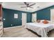 The main bedroom has a ceiling fan, large window, light colored wood floors, and a white bed at 7722 W Pipestone Pl, Phoenix, AZ 85035