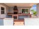 Covered outdoor kitchen with a brick built-in grill, perfect for BBQ's, and tiled counters, blending functionality at 100 E Geneva Dr, Tempe, AZ 85282
