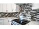 Close up of stainless steel stove and black, gray and white mosaic backsplash and white granite countertops at 10910 N Thunderbird Rd, Maricopa, AZ 85139