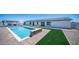Beautiful pool area featuring a stone accent wall, artificial turf, and a view of the home's exterior at 10910 N Thunderbird Rd, Maricopa, AZ 85139