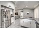 Open kitchen with stainless steel refrigerator, white cabinets, and breakfast bar overlooking the living area at 12543 W Roanoke Ave, Avondale, AZ 85392