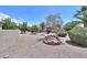 Lush backyard with low-maintenance landscaping, mature trees, and a charming brick fire pit at 135 S Verde Ln, Casa Grande, AZ 85194
