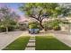 Inviting backyard featuring desert landscaping, artificial turf, and a cozy seating area beneath a mature shade tree at 14945 N 102Nd St, Scottsdale, AZ 85255