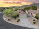 Charming home with a desert landscape, spacious driveway, and scenic mountain views during a vibrant sunset at 14945 N 102Nd St, Scottsdale, AZ 85255
