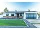 A charming home with a green lawn, brick accents, and a modern black-framed glass garage door at 1539 W Puget Ave, Phoenix, AZ 85021