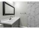 Modern bathroom featuring marble shower, gray vanity with white countertop and black framed mirror at 1828 W Tuckey Ln # 13, Phoenix, AZ 85015