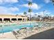 Resort-style pool offers ample seating with palm trees, blue skies, and shade umbrellas for relaxing community living at 272 S Cinnabar Dr, Apache Junction, AZ 85119