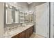 Bathroom featuring dual sinks with granite countertops, decorative mirrors, lighting, and neutral colored tile flooring at 2727 S Balboa Dr, Gilbert, AZ 85295