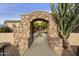 Stone archway offers a glimpse into a lush courtyard with a fountain, creating a serene and inviting entrance at 2727 S Balboa Dr, Gilbert, AZ 85295