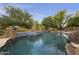 Stunning swimming pool featuring a decorative stone waterfall, mature trees, and desert landscaping at 2727 S Balboa Dr, Gilbert, AZ 85295