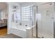 Bright bathroom featuring a glass enclosed shower, tub, and light colored tile at 29798 N 121St Dr, Peoria, AZ 85383