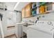 Functional laundry room equipped with a washer, dryer, utility sink, and shelving for storage, plus natural light at 3146 W Paradise Dr, Phoenix, AZ 85029