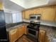 Modern kitchen with stainless steel appliances, granite countertops, and light wood cabinets at 3420 W Danbury Dr # C218, Phoenix, AZ 85053