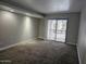 Spacious living room with neutral walls, plush carpet, and sliding glass doors leading to a balcony at 3420 W Danbury Dr # C218, Phoenix, AZ 85053