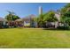 Spacious backyard boasts a manicured lawn, mature trees, and a charming pergola-covered area, ideal for relaxation at 3949 E Norcroft Cir, Mesa, AZ 85215