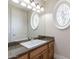 Bathroom featuring wood cabinet with granite counter, vanity, mirror, and custom window at 3949 E Norcroft Cir, Mesa, AZ 85215