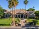 Stately home featuring lush landscaping, towering palm trees, a circular driveway, and a welcoming water fountain at 3949 E Norcroft Cir, Mesa, AZ 85215