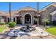 Close-up of the gorgeous front entrance with a stone archway, double doors, fountain, and manicured landscaping at 3949 E Norcroft Cir, Mesa, AZ 85215