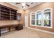 Home office boasts custom built-ins, a ceiling fan, and large arched windows for ample natural light at 3949 E Norcroft Cir, Mesa, AZ 85215