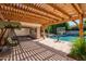 Covered outdoor patio with a pergola, lush landscaping, and view of the pool at 3949 E Norcroft Cir, Mesa, AZ 85215