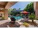Relaxing pool area with waterfall feature, shaded by vibrant umbrellas and lush greenery at 3949 E Norcroft Cir, Mesa, AZ 85215