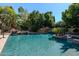 Backyard swimming pool with rock waterfall feature surrounded by palm trees and lush landscaping, creating a private oasis at 3949 E Norcroft Cir, Mesa, AZ 85215