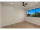 Bright and airy bedroom with hardwood floors, ceiling fan, and a large window with green tree view at 4911 E Amelia Ave, Phoenix, AZ 85018