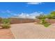 View of the fenced backyard features a brick-paved area, a grassy area, and mature trees at 5123 W Novak Way, Laveen, AZ 85339