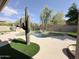 Backyard pool featuring a rock waterfall, artificial turf, outdoor grill, and desert landscaping at 6931 E Teton Cir, Mesa, AZ 85207