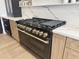 Stainless steel gas range with light wood cabinetry, white countertops, and black accents at 6931 E Teton Cir, Mesa, AZ 85207