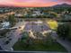 Beautiful aerial view of estate with lush landscaping, sport court, and city views at sunset at 7129 E Caron Dr, Paradise Valley, AZ 85253