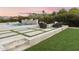 Resort style backyard featuring a cascading waterfall, a fire pit area, lush landscaping and green grass at 7129 E Caron Dr, Paradise Valley, AZ 85253