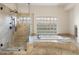 Luxurious bathroom with a walk-in shower, soaking tub, and decorative glass block window at 7129 E Caron Dr, Paradise Valley, AZ 85253