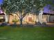 Charming home with mature trees, a fountain, and a well-manicured lawn at twilight at 7129 E Caron Dr, Paradise Valley, AZ 85253