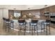 Gourmet kitchen featuring a curved stone island with seating, custom cabinetry, and stainless steel appliances at 7129 E Caron Dr, Paradise Valley, AZ 85253