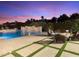 Inviting pool area featuring a waterfall feature, hot tub, and cozy seating around a fire pit against a vibrant sunset backdrop at 7129 E Caron Dr, Paradise Valley, AZ 85253