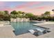 Gorgeous pool featuring a stone waterfall, lounge chairs in the water, a spa and lush landscaping at sunset at 7129 E Caron Dr, Paradise Valley, AZ 85253