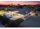Stunning rear exterior with a pool, spa, and well-manicured landscaping at twilight at 7129 E Caron Dr, Paradise Valley, AZ 85253